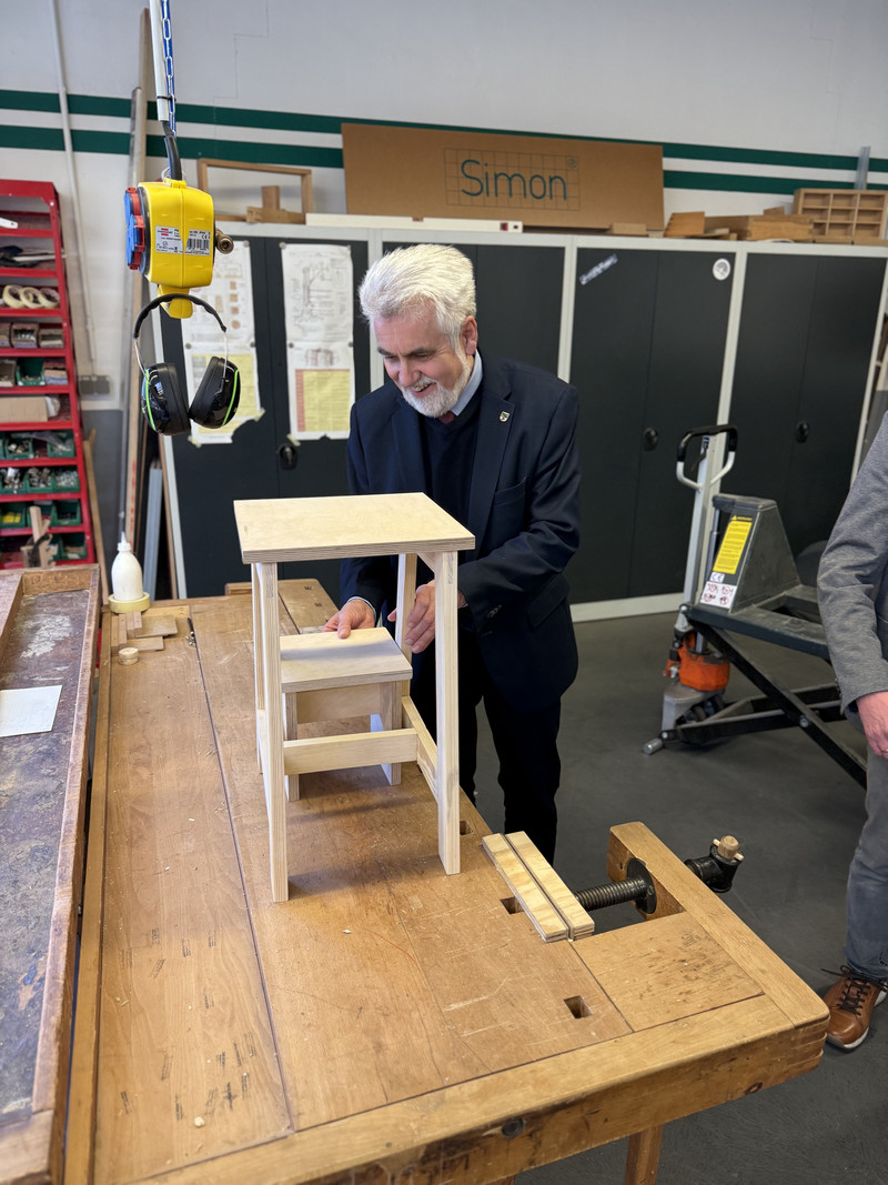 Minister Willingmann sieht sich ein Objekt aus Holz an.