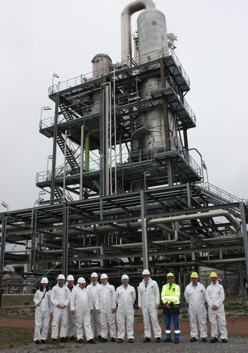 Gruppenfoto der Teilnehmenden des Unternehmensbesuch von Solvay. Die Teilnehmenden stehen vor einer technischen Anlage im Außengelände.