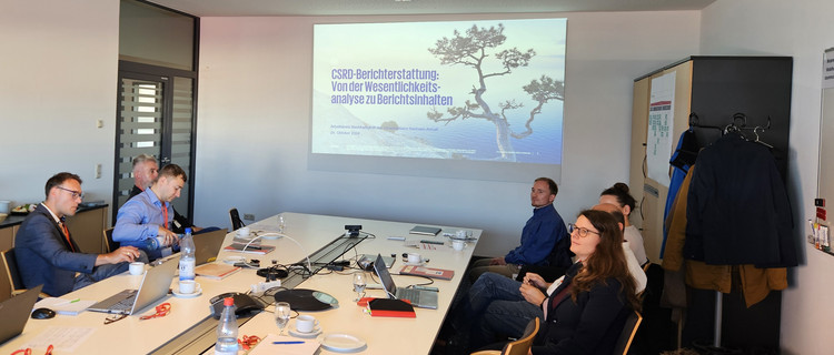 Teilnehmende des Arbeitskreises Nachhaltigkeit schauen sich eine Präsentation zum Thema "CSRD-Berichterstattung: Von der Wesentlichkeitsanalyse zu Berichtsinhalten" an.